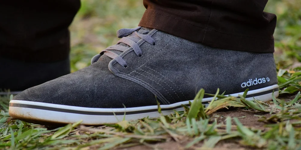 Close-up of a gray suede Adidas shoe on grass