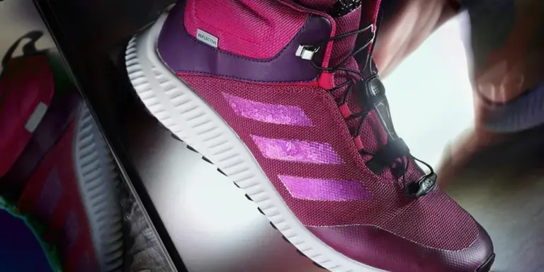 Close-up of a purple and pink athletic sneaker with a white sole and three pink stripes