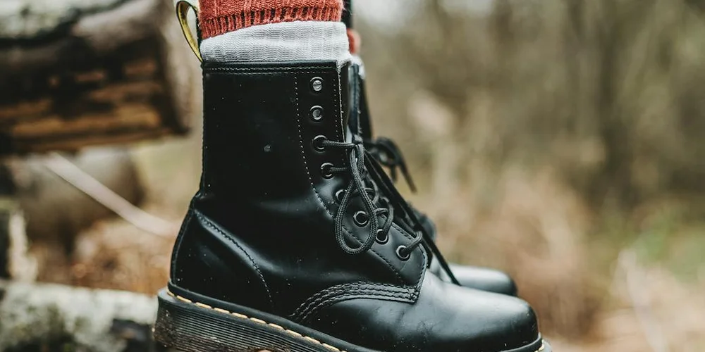 Close-up of a black leather boot with laces outdoors, ready for restoration.