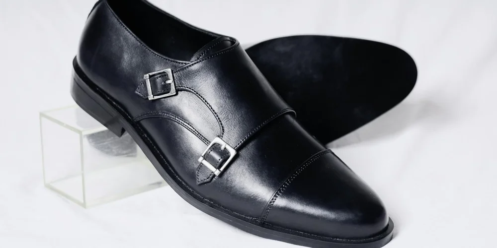 Black leather dress shoe with double-buckle straps on a white background