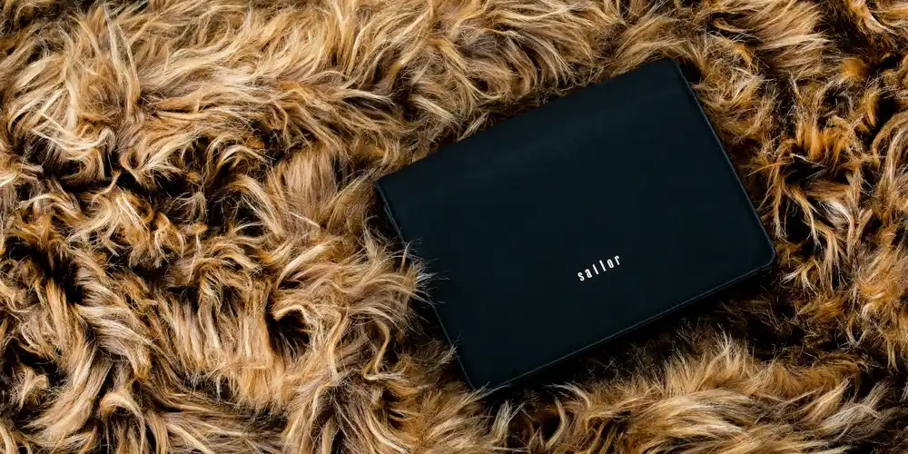 Black leather purse resting on a fluffy tan fur surface, ready for cleaning prep.