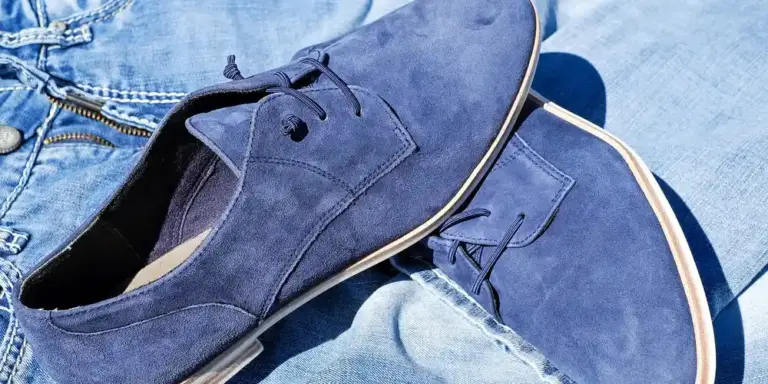 Close-up of blue suede shoes resting on denim fabric, highlighting the nap-friendly material.