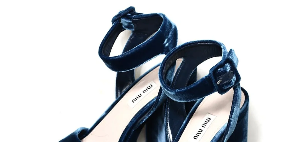 Close-up of blue suede sandals with ankle straps on a white background