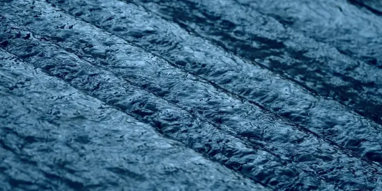 Close-up of a blue textured rug surface with soft, wavy fiber-like patterns.