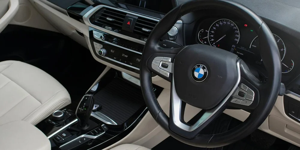 Cream-colored leather car seats and a leather-wrapped steering wheel in a BMW, showing a clean, well-maintained cabin