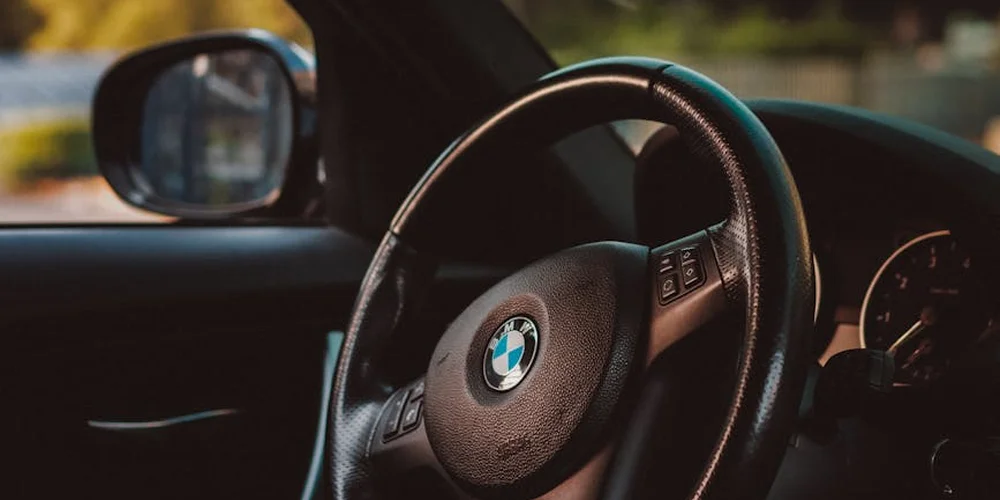 Close-up of a leather-wrapped BMW steering wheel inside a car