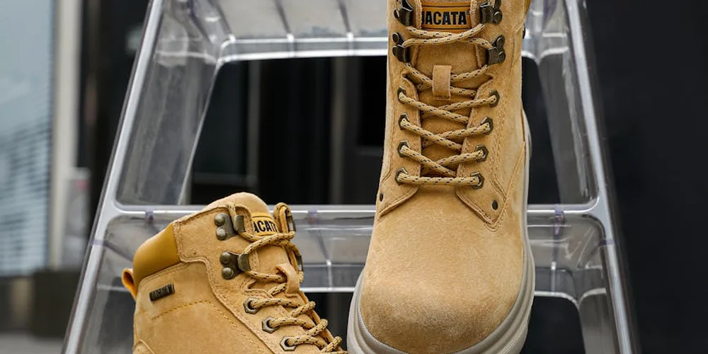 Tan suede boots with laces resting on a metal display rack.