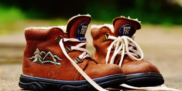 Close-up of brown leather hiking boots with white laces, worn outdoors.
