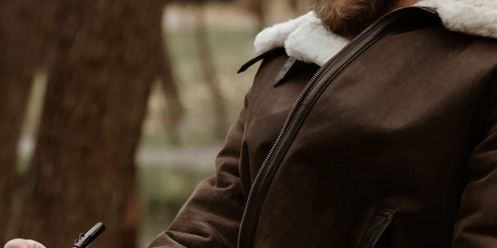 Close-up of a brown leather motorcycle jacket with a shearling-lined collar and visible zipper.