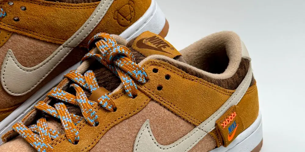Close-up of brown and tan suede sneakers with white soles and blue-orange patterned laces
