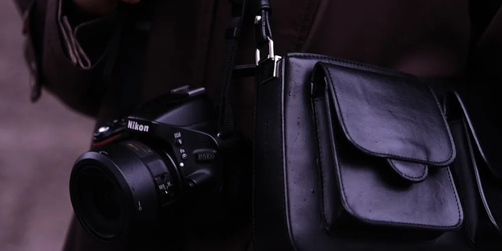 A Nikon camera rests beside a black leather purse, illustrating a common accessory paired with safe ink-removal steps.