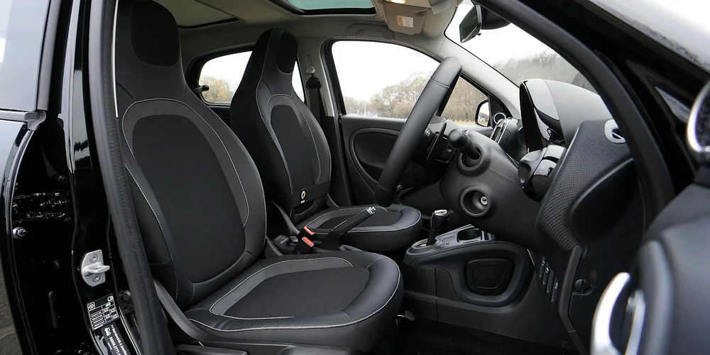 Car interior with dark gray faux-leather seats and dashboard, illustrating daily care to prevent peeling