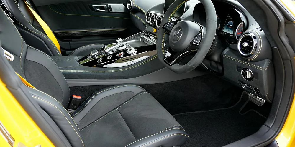Yellow sports car interior featuring black coated leather seats, metal trim, and a driver-focused cockpit