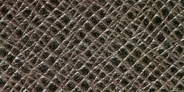 Close-up image of dark brown cowhide leather showing a diamond-like grain pattern and subtle gloss.