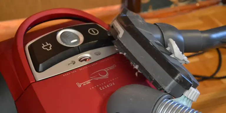 Vacuum cleaner head on a wooden floor, representing cleaning tools for cowhide rugs.