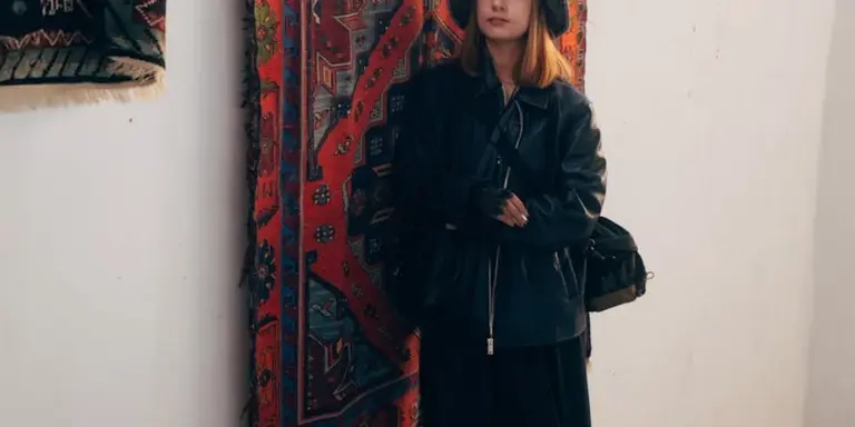 Person in a dark jacket standing beside racks of cowhide and sheepskin rugs on display