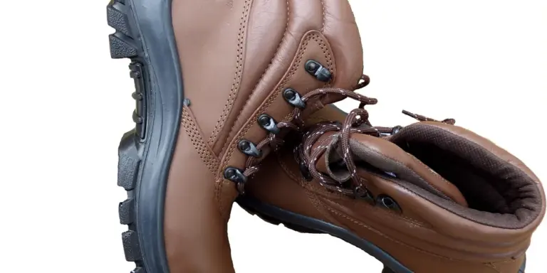 Close-up of a brown leather boot with laces and a rugged sole, showing creases in the leather.