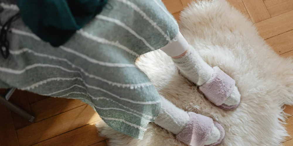 Feet in cozy socks stepping on a plush sheepskin rug