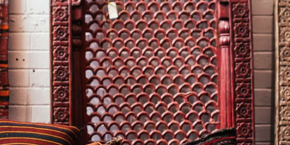 Close-up of a decorative red metal gate with circular patterns against a brick wall.