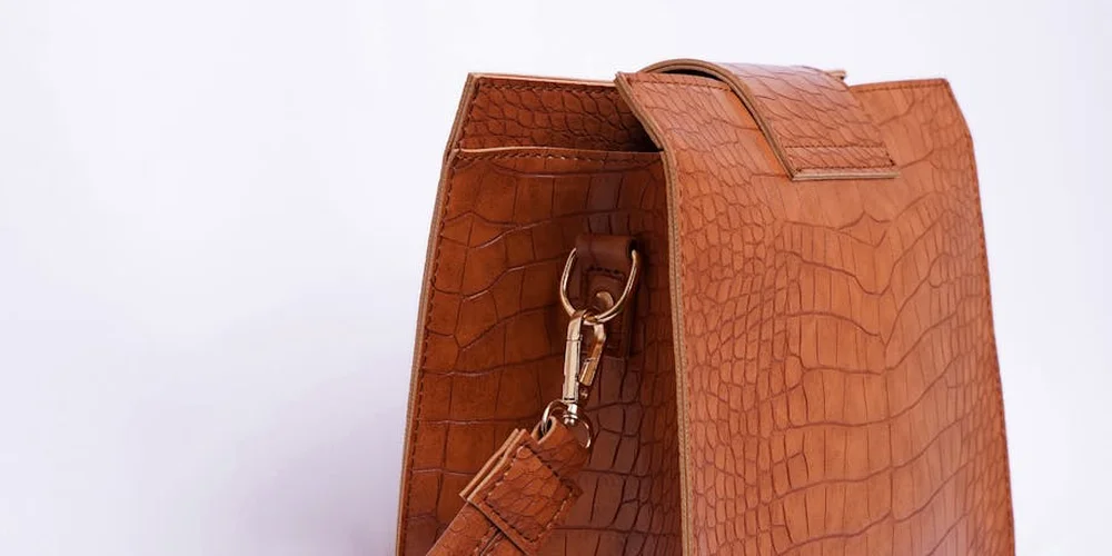 Brown crocodile-pattern luxury handbag showing edge seam and hardware, illustrating edge details to examine.