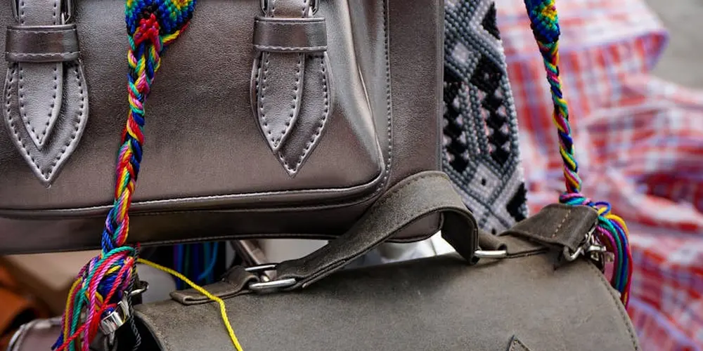Close-up of a brown faux leather bag with colorful braided cords and stitching.