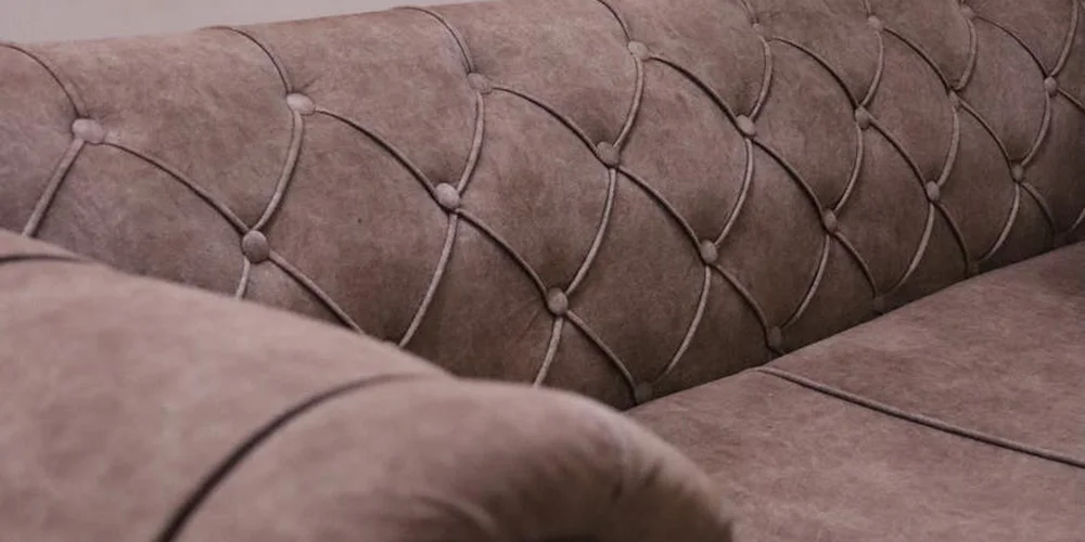 Close-up of a brown tufted faux suede sofa upholstery.