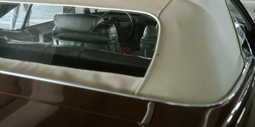 Cream-colored leather car seats inside a vintage vehicle with a dark interior.