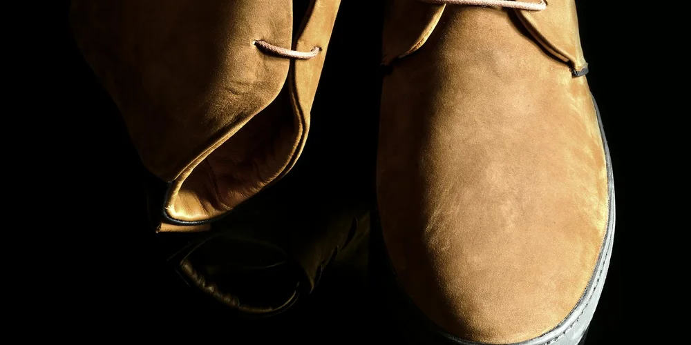 Close-up of tan suede boots on a dark background