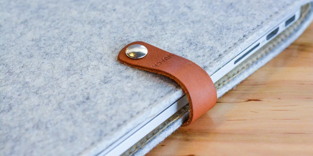 Close-up of a brown leather strap with a metal snap resting on a gray fabric-covered surface