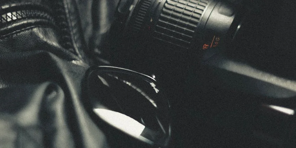 Close-up of black leather fabric with a camera lens in the background.