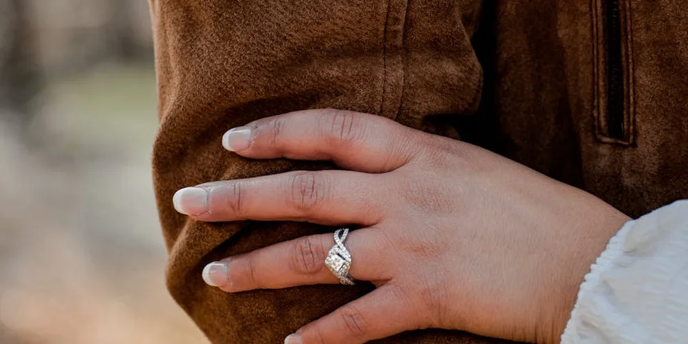 Close-up of a hand with a ring resting on a brown suede sleeve