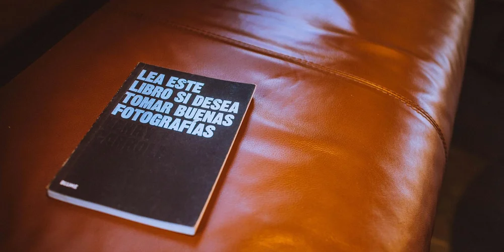 Close-up of a brown leather surface with a black notebook resting on it.