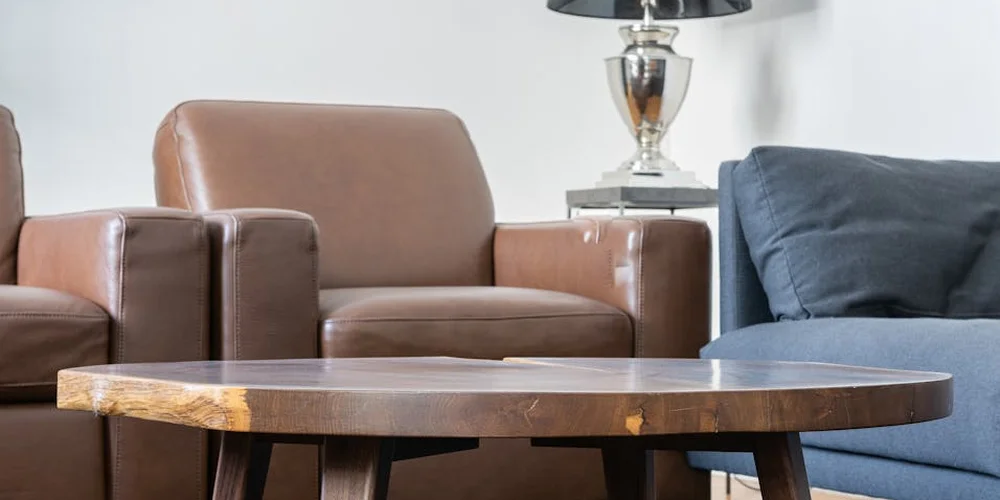 Living room scene with tan and brown leather sofas and a round wooden coffee table, illustrating durable leather furniture.