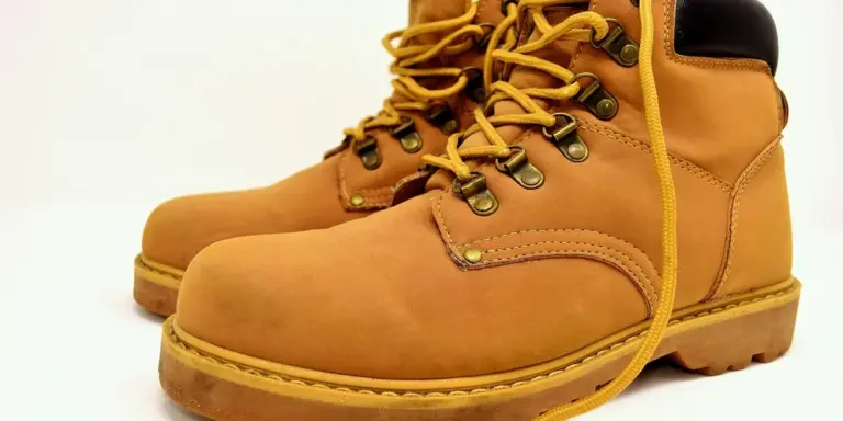 Tan leather boots with yellow laces on a white background