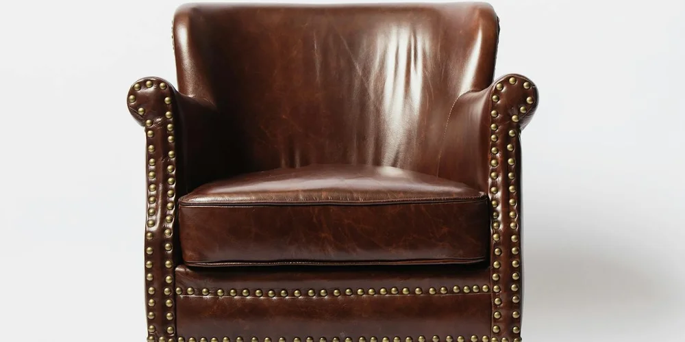 Brown leather chair with brass nailhead trim and a smooth, glossy finish.