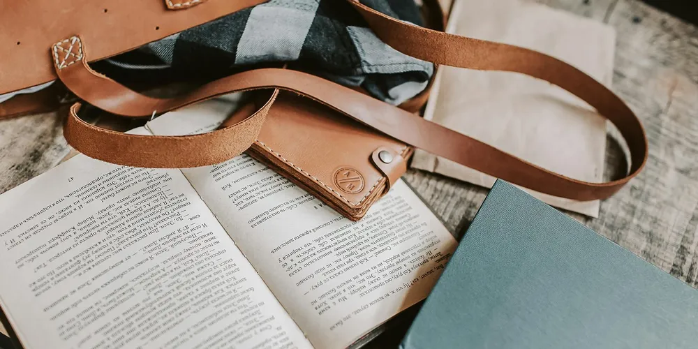 Brown leather straps resting on open books, illustrating leather goods awaiting maintenance.