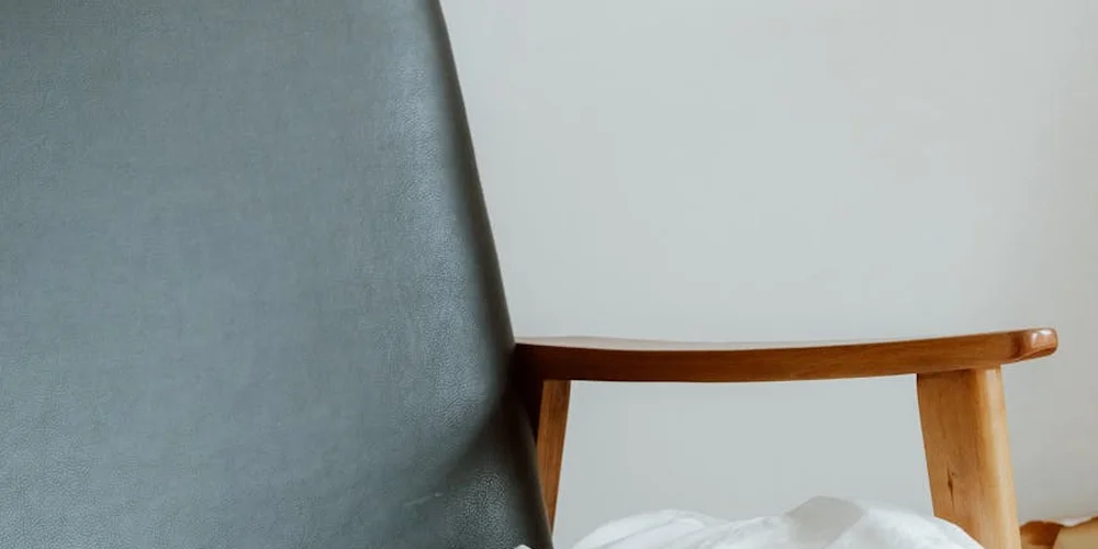 Close-up of a gray leather chair with a wooden armrest