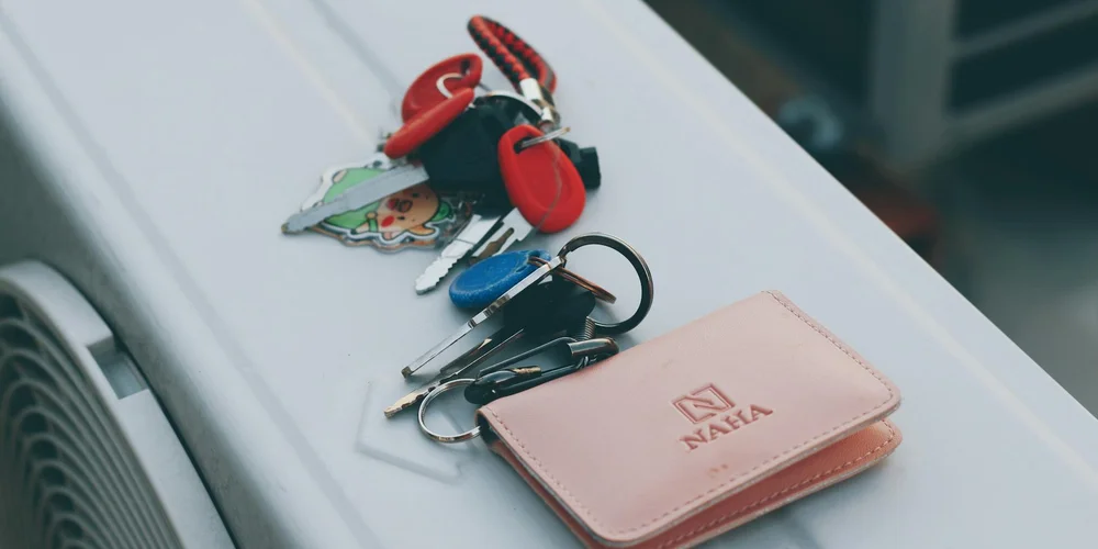 A pink leather wallet with multiple metal keys and keychains resting on a light surface.