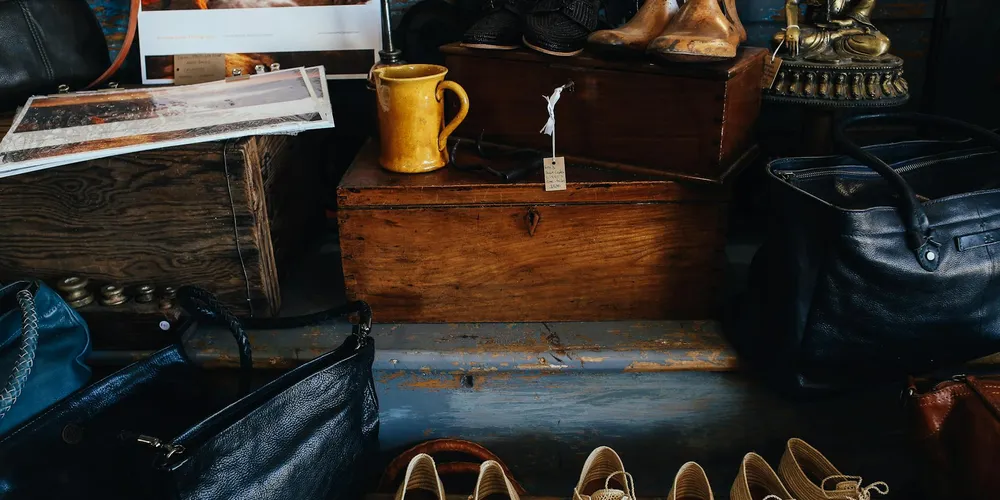 Scene of a vintage leather goods display featuring wooden boxes, shelves, boots, bags, and a mug, illustrating leather care through time.
