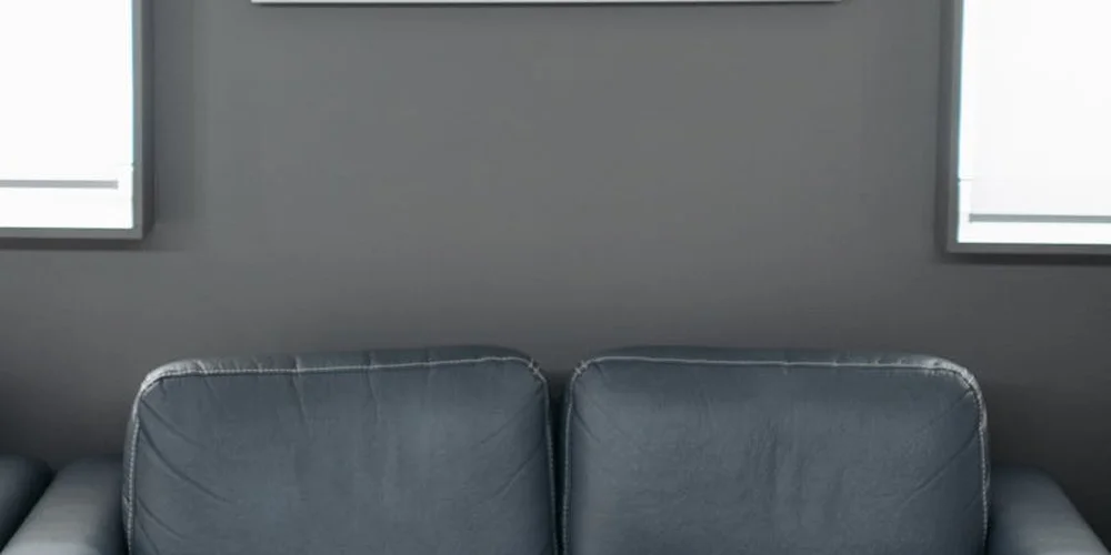 Two dark leather cushions on a worn leather sofa against a dark wall, with visible creases and edge wear.