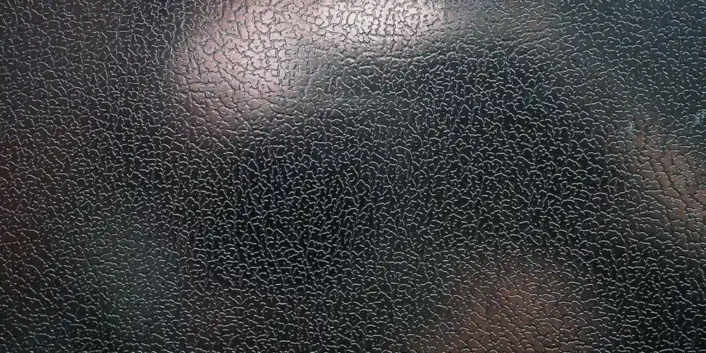 Close-up of a black leather couch surface with visible grain and minor wear, suggesting a moderate scratch scenario.