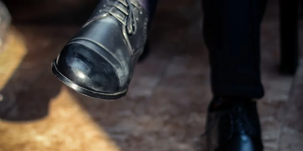 Close-up of a dark blue leather dress shoe with laces, shown at a slight angle to highlight the leather finish.