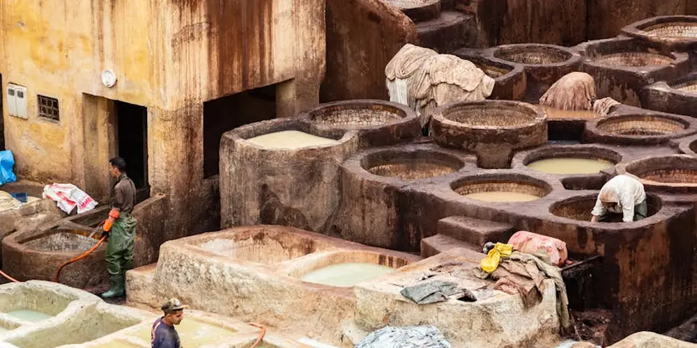 Leather tannery with large circular dye vats and workers handling the dye