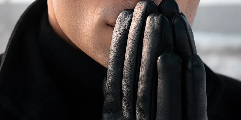 Close-up of hands in black leather gloves pressed together