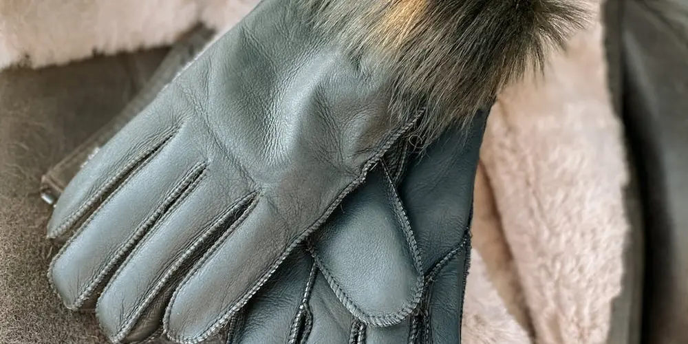 Close-up of gray leather gloves with fur trim at the wrist.