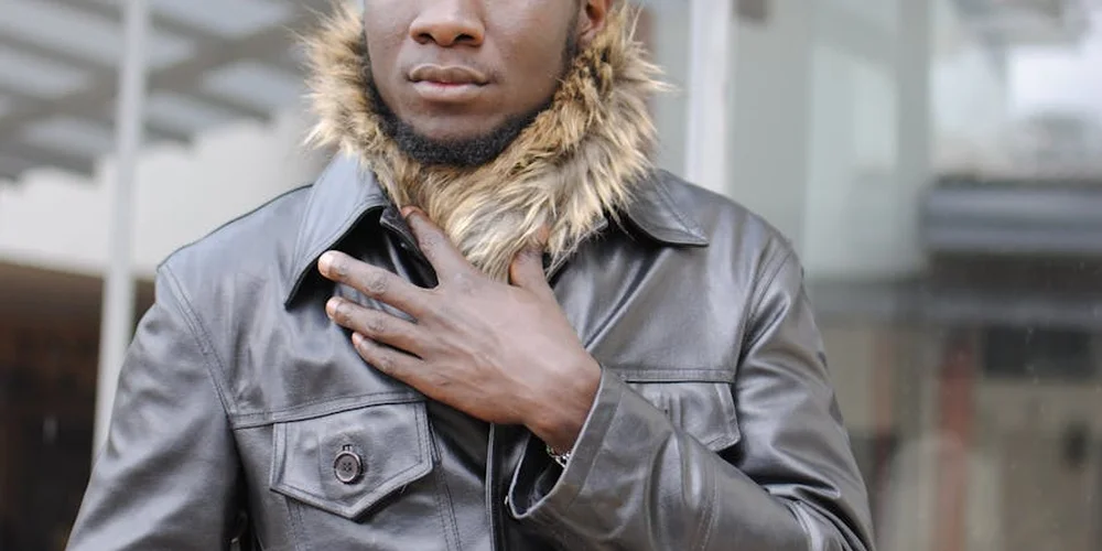 Person wearing a dark leather jacket with a fur-lined hood.