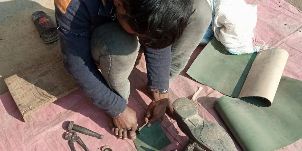 Person kneeling on the floor, arranging leather patches and repair tools for a leather repair project.