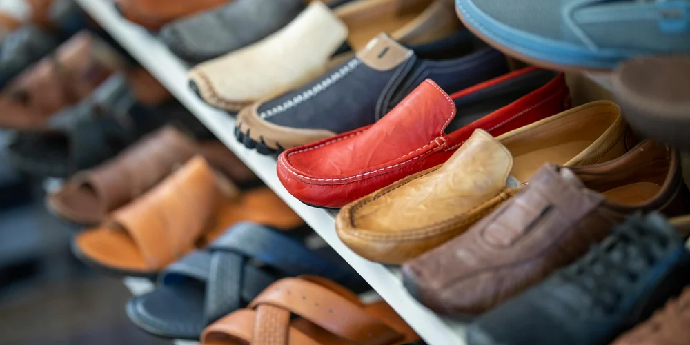 Assorted leather footwear—loafers and boots—in a variety of colors arranged on a display shelf.