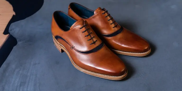Brown leather dress shoes resting on a blue-gray surface