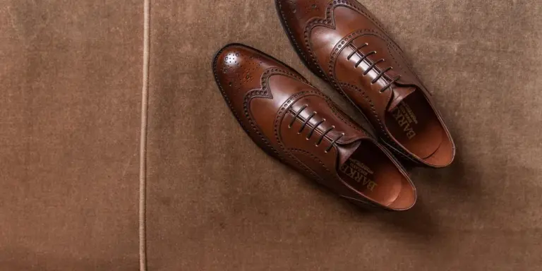 Brown leather dress shoes on a cardboard surface, ready for at-home dyeing.